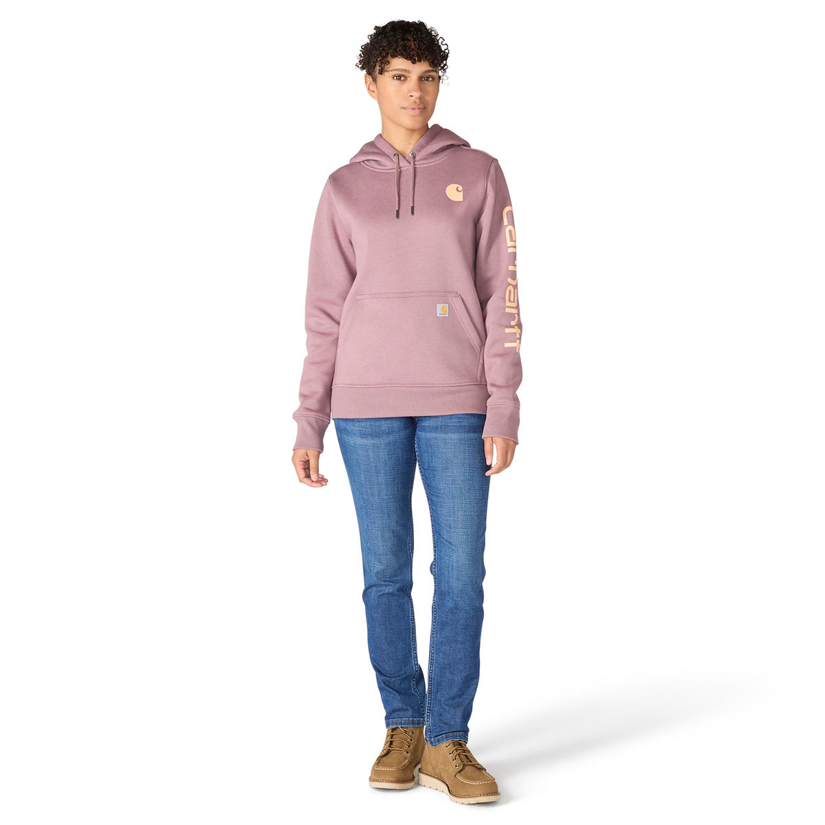 Person wearing a pink hoodie with a brand logo, blue jeans, and brown boots on a white background