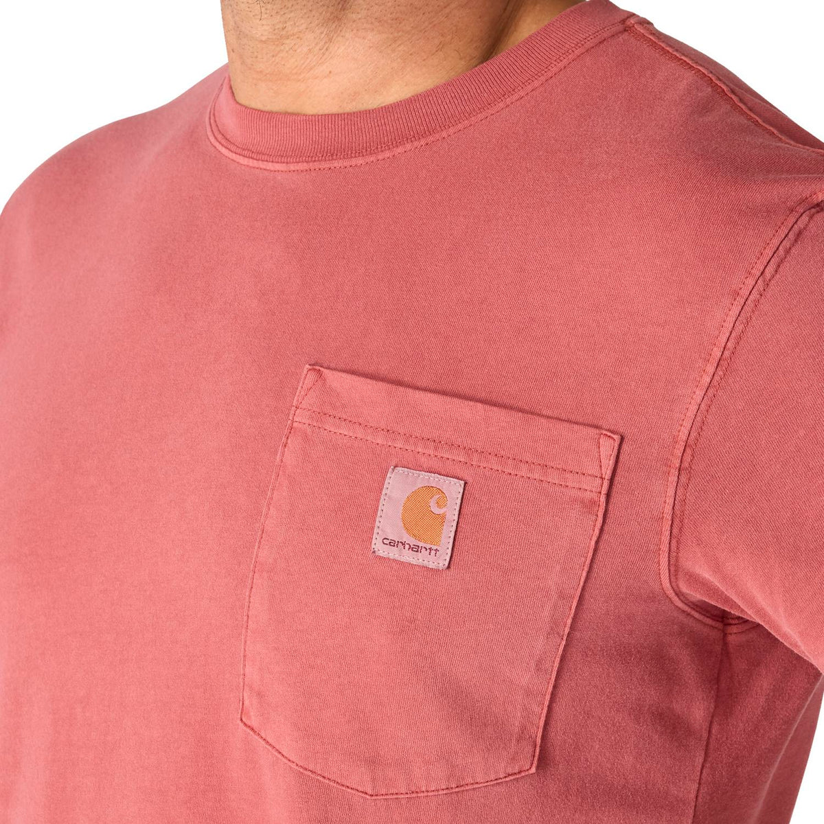 Close-up of a pink t-shirt with a Carhartt logo on the chest pocket against a white background