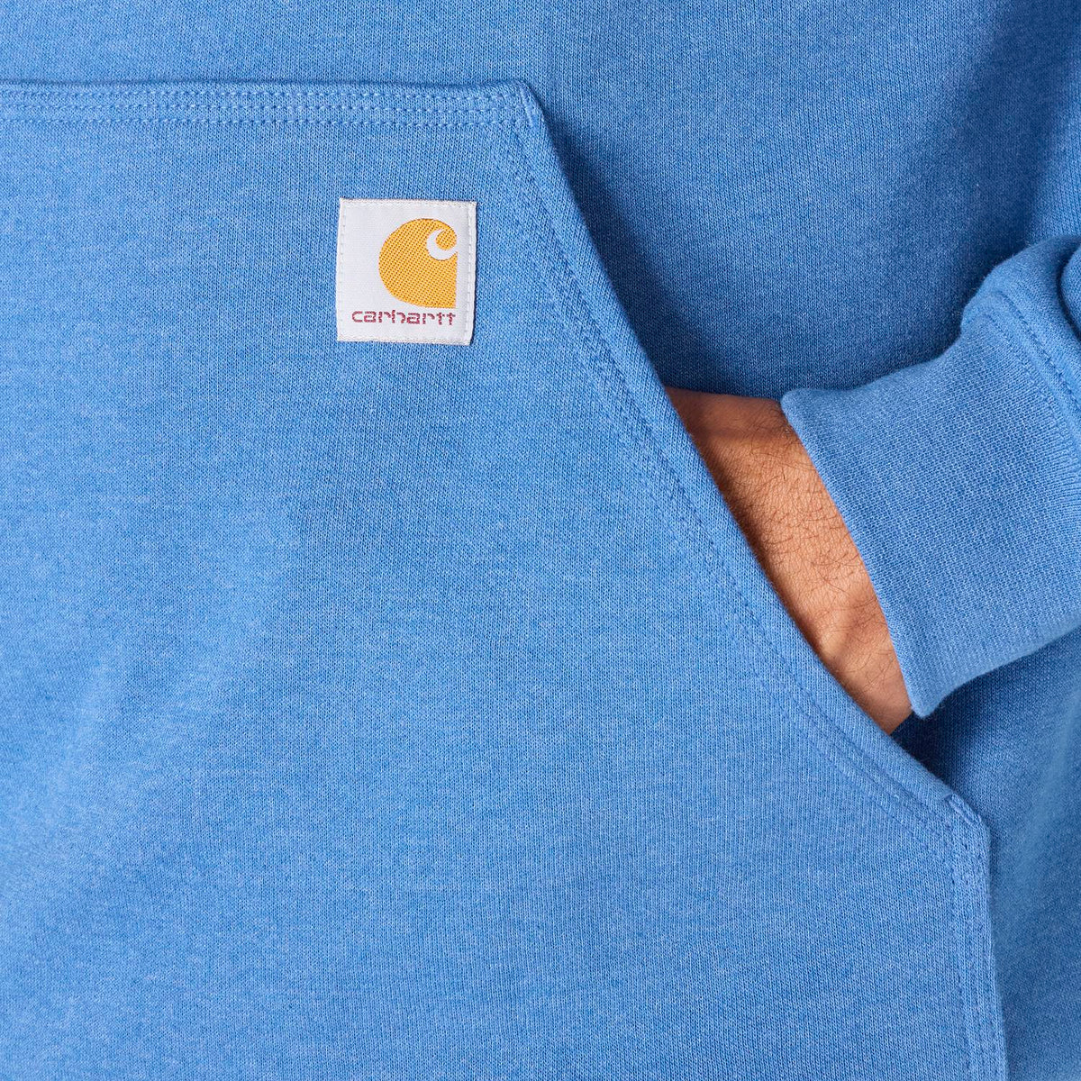 Close-up of a blue sweatshirt with a Carhartt logo on the chest pocket.