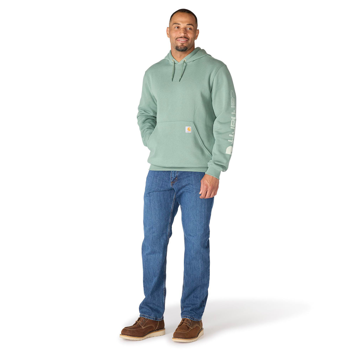 Man wearing a light green hoodie and blue jeans on a white background